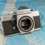 Classic Praktica MTL3 film camera placed on a textured blue surface, showcasing retro design.