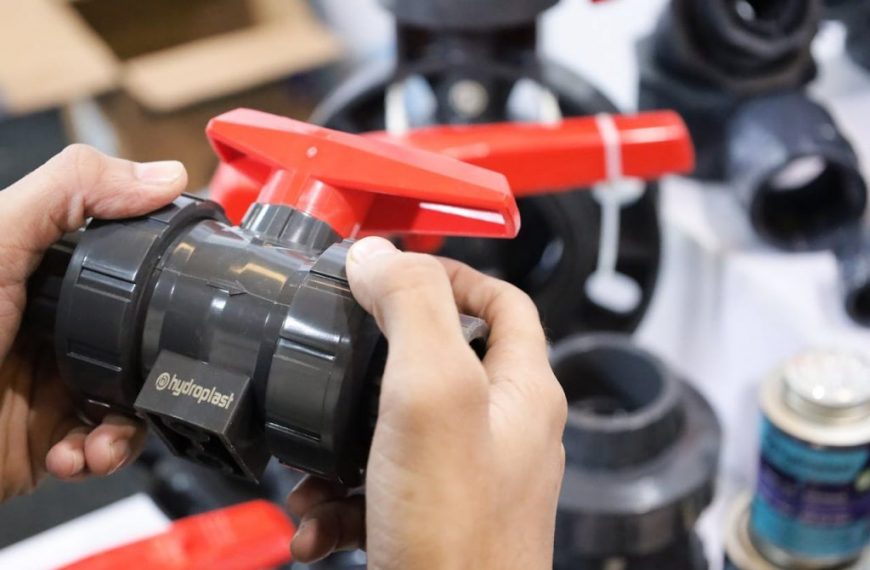 Close-up of hands examining a Hydroplast industrial valve at a trade expo.