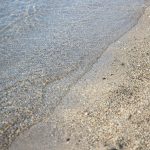 Close-up of a tranquil beach with gentle waves lapping at the sandy shore.